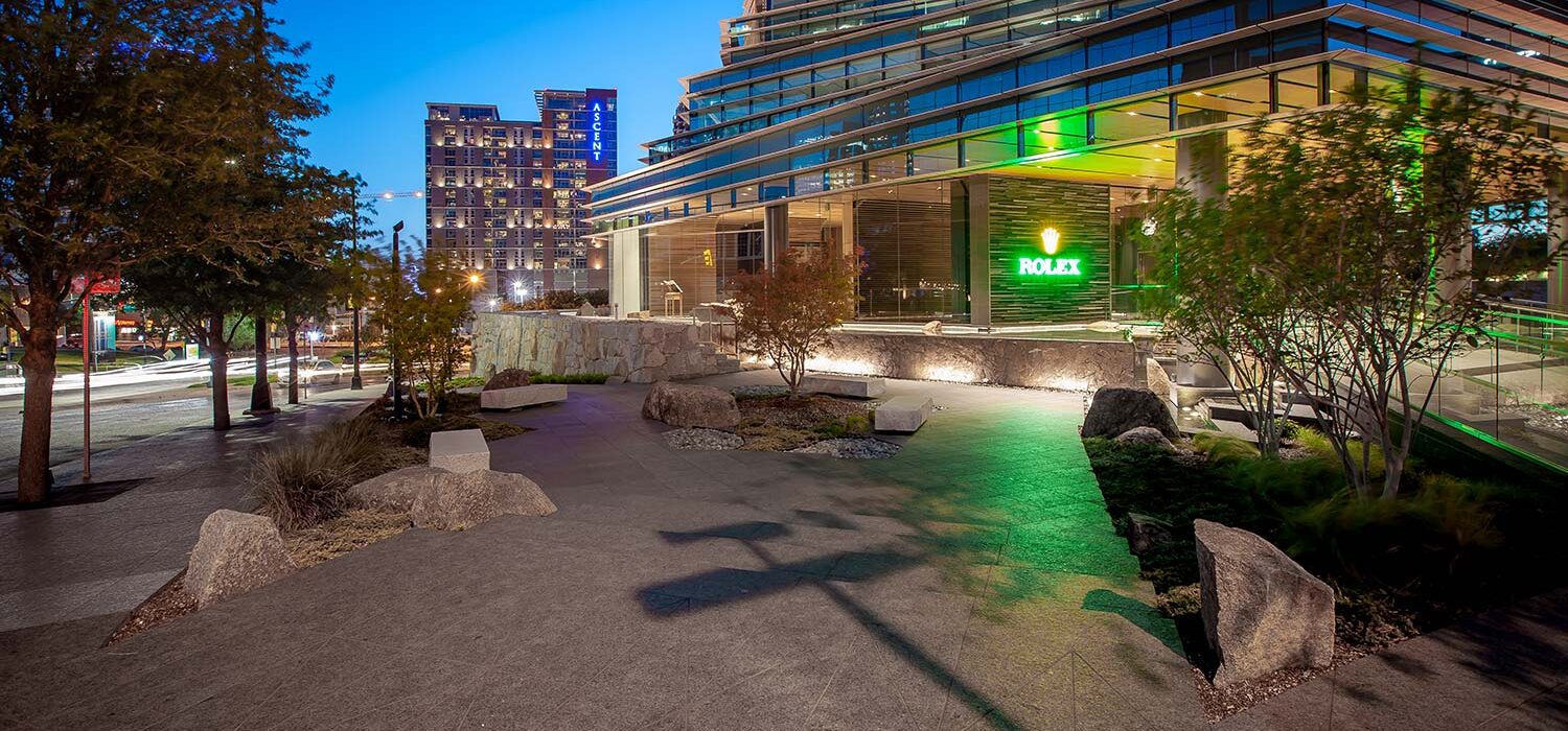 Rolex Building plaza at night with Dallas cityscape